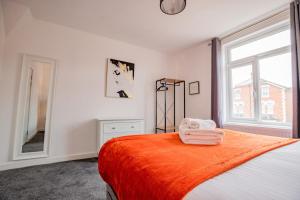 ein Schlafzimmer mit einem Bett mit einer orangefarbenen Decke und einem Spiegel in der Unterkunft Bromyard Flat 3 - Relax & Unwind in Worcester