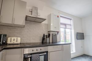 eine Küche mit weißen Schränken und einem Herd mit Backofen in der Unterkunft Bromyard Flat 3 - Relax & Unwind in Worcester + 15 Fotos