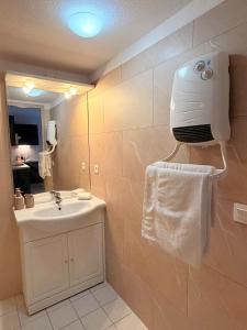 a bathroom with a sink and a towel dispenser on the wall at Le Clos de Beaune in Levernois +10 photos