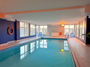 a large swimming pool with blue chairs in a building at Le Clos de Beaune in Levernois