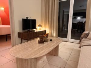 a living room with a table and a flat screen tv at Le Clos de Beaune in Levernois