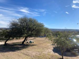 een park met een bank, bomen en een rivier bij Lucero de Brochero in Villa Cura Brochero +8 foto's
