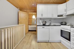 a kitchen with white cabinets and white appliances at Pyhäkoti C - 30 Metres From the Slopes - Valkea Homes in Pyhätunturi +22 photos