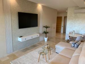 a living room with a couch and a tv on a wall at appartement prestige golf city in Marrakech