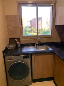a kitchen with a dishwasher and a sink and a window at appartement prestige golf city in Marrakech