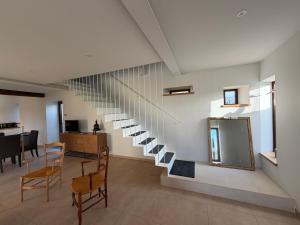 a staircase in a room with chairs and a table at Le Pressoir, maison au calme, jardin, terrasse, 3 chambres, 2 sdb, 2 WC, proche Bayeux et Arromanches au coeur des plages du débarquement in Longues-sur-Mer