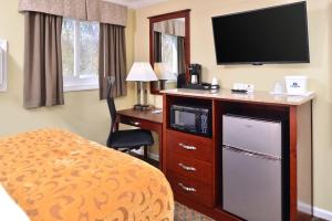 a hotel room with a television and a bed and a desk at Cheshire Welcome Inn in Cheshire