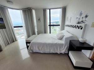 a white bedroom with a bed and a large window at Apartamento Ejecutivo Premium Riviera Tower in Villa Carlos Paz