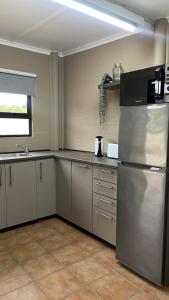 Il comprend une cuisine équipée d'un réfrigérateur en acier inoxydable et une fenêtre. dans l'établissement Houtbosch Farm Stay, à George