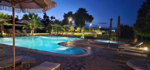 een zwembad met stoelen en parasols in de nacht bij Resort Comfort Long Beach in Ulcinj