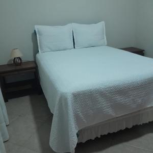 een bed met witte lakens en kussens in een kamer bij Casa Valen com 2 quartos in Rio de Janeiro