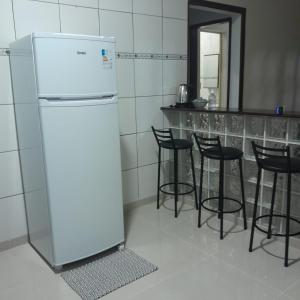 een witte koelkast in een keuken met zwarte krukken bij Casa Valen com 2 quartos in Rio de Janeiro