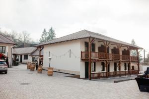 a white building with a porch and a balcony at Pensiunea Draser in Şeica Mică