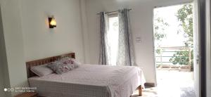 a bedroom with a bed and a large window at Oak Hill Cottage in Mussoorie
