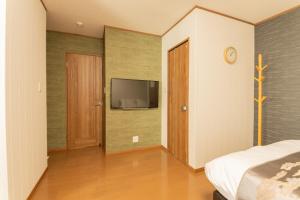 a bedroom with a bed and a television on a wall at 九洲別苑 in Osaka