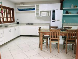 a kitchen with white cabinets and a table and chairs at Pousada Perequê in Ilhabela