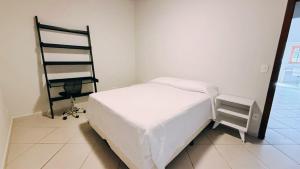 a bedroom with a white bed and a chair at Pousada Perequê in Ilhabela