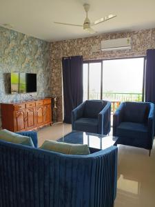 a living room with two blue chairs and a tv at Namaste sea view apartment in Canacona