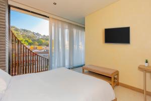 a bedroom with a bed and a balcony with a television at Iconik Hotel in Medellín