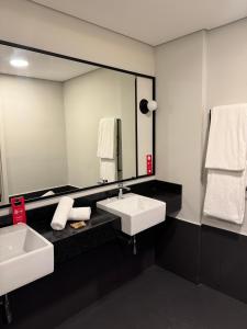 un bagno con due lavandini e un grande specchio di IBIS PRIMAVERA DO LESTE a Primavera do Leste Altre 59 foto