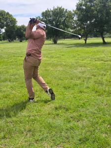 a man swinging a golf club in a field at Bushman Spoor Backpackers in Soweto