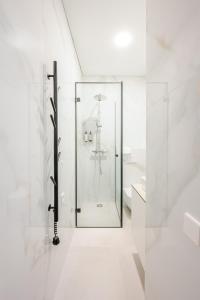 ein weißes Bad mit einer Glasduschkabine in der Unterkunft Center Gallery Apartment in Kaunas