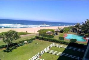 uitzicht op het strand vanaf het balkon van een resort bij Inyoni Rocks Cabanas 15 in Amanzimtoti