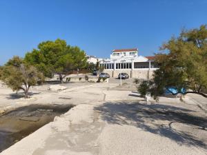 a large white house with trees in front of it at Pansion Danilo by the sea in Krmčina