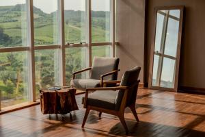 two chairs and a table in a room with windows at Casa Valduga Pousada Boutique in Bento Gonçalves