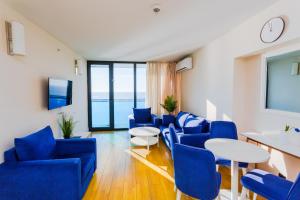 Orbi city Aparthotel في باتومي: غرفة بها كراسي زرقاء وطاولة وتلفزيون