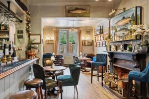 亨利昂泰晤士Flower Pot Hotel的酒吧配有桌椅和钢琴 更多28张照片