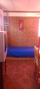 a room with a blue bed in a brick wall at Bella Fefi in Villa Cura Brochero