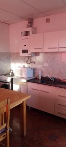 a kitchen with white cabinets and a wooden table at Bella Fefi in Villa Cura Brochero