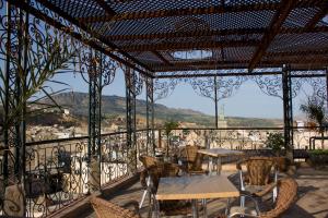 a patio with tables and chairs and mountains in the background at Hotel Bab Boujloud in Fez