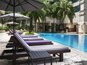 een zwembad met ligstoelen en parasols naast een gebouw bij Pullman Kuala Lumpur City Centre Hotel & Residences in Kuala Lumpur