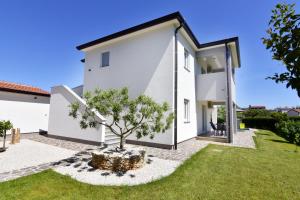 a white house with a tree in the yard at Relaxing holiday home with shared pool in Čepljani