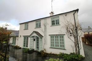 a white house with green shuttered windows at Brookside, Hawkshead in Hawkshead