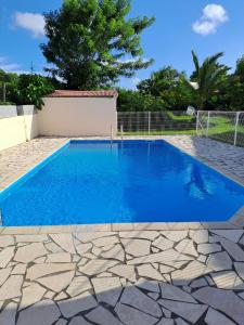a swimming pool with blue water in a yard at Le Paradis bleu in Sainte-Anne