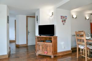 einen TV auf einem Holzständer im Wohnzimmer in der Unterkunft Le Chat De Lamartine - Clim Parking in Saint-Pierre-dʼAlbigny