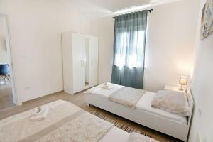 a white bedroom with a bed and a window at Modern holiday home with shared pool in Čepljani +56 photos