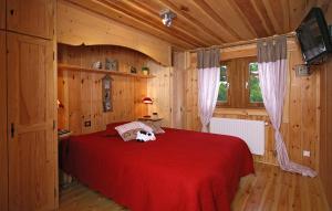 a bedroom with a red bed in a wooden room at Odalys Chalet Leslie Alpen in Les Deux Alpes