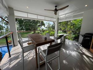 a dining room with a table and chairs on a balcony at BIG Beach House Tranquility in Kewarra Beach