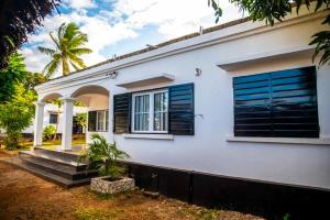 een wit huis met blauwe luiken en trappen bij Maison avec Jardin à la Pyrot in Diego Suarez
