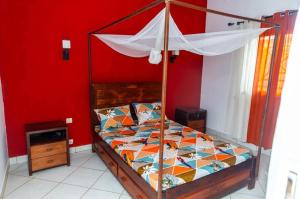 een bed in een kamer met een rode muur bij Maison avec Jardin à la Pyrot in Diego Suarez +28 foto's