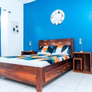 een slaapkamer met een groot houten bed met een blauwe muur bij Maison avec Jardin à la Pyrot in Diego Suarez