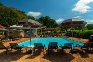 a pool with tables and chairs and umbrellas at Hotel Colonial Iguaçu in Foz do Iguaçu