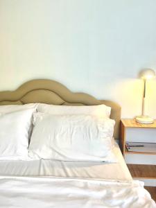a bed with white sheets and a lamp on a table at Yada House Alina Cottage in Nai Yang Beach