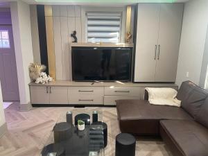 a living room with a couch and a large television at Modern 7 Bedroom Masterpiece on Portage Sleeps 16 in Niagara Falls
