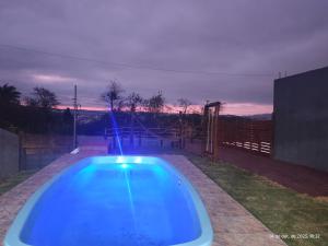 a blue swimming pool in a backyard at night at Casa com piscina,tipo kitnet, próximo ao Centro in Cotia
