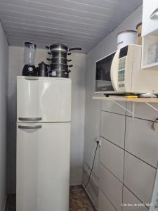 a small kitchen with a refrigerator and a microwave at Casa com piscina,tipo kitnet, próximo ao Centro in Cotia